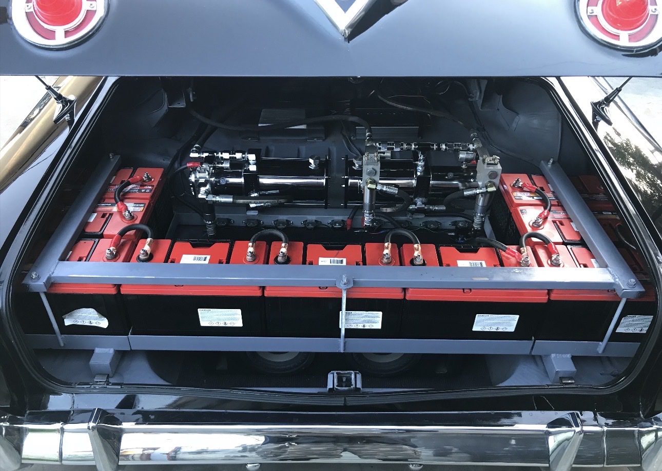 Lowrider trunk setup with red batteries and hydraulic pumps